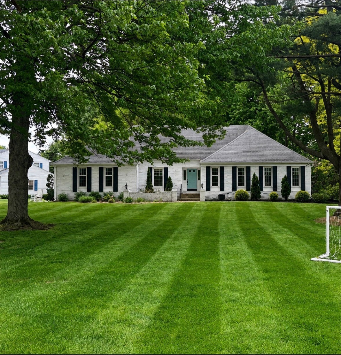 Freshly mowed residential lawn in front of a white brick home.